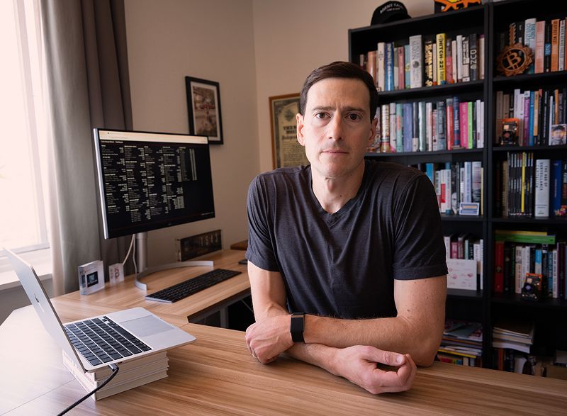 Alex Gladstein sitting at a desk in front of a bookshelf.